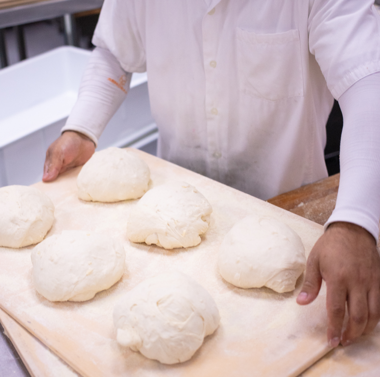 Baker holding tray of bread dough