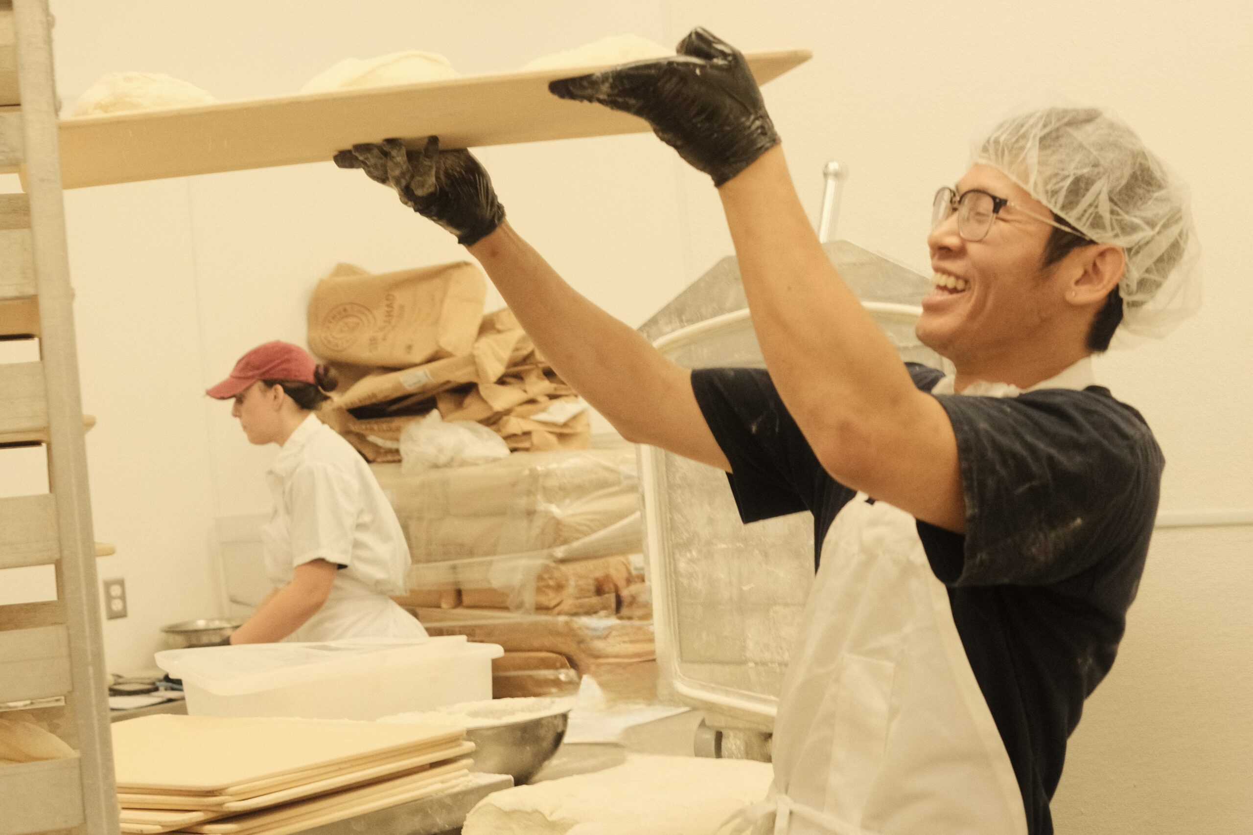 Baker holding tray of bread dough